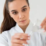 Femeie in halat alb care toarna niste apa dintr-un pahar