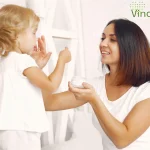 Mama punand crema pe fata fetitei sale