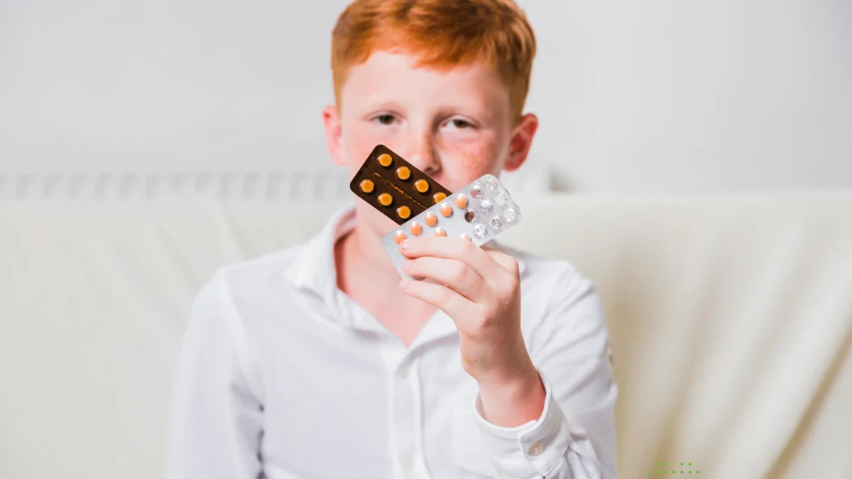 Copil pistruiat care tine mai multe pastile in mana