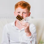 Copil pistruiat care tine mai multe pastile in mana