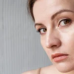 Femeie care observa daca are piele uscata in camera